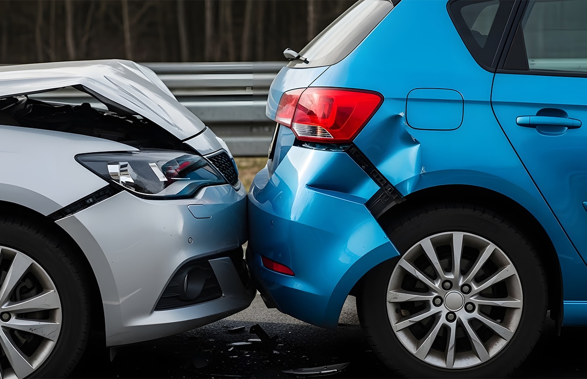 Dos vehículos detenidos tras una colisión por alcance, con daños visibles en el parachoques trasero de un coche y el frontal del otro, en una vía con barrera metálica al fondo
