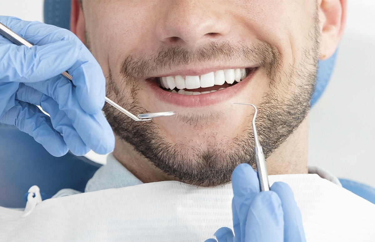 Procedimiento dental con instrumental clínico aplicado sobre la dentadura, con guantes y herramientas visibles en primer plano