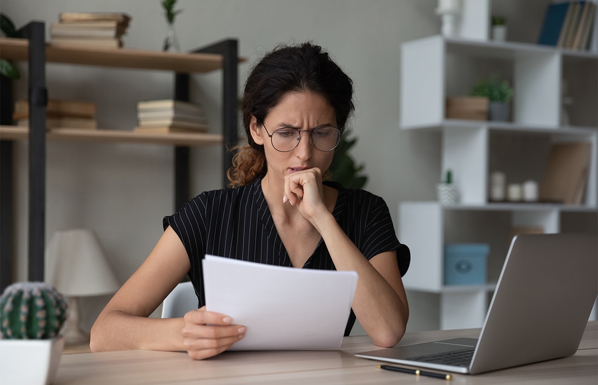 Mujer con cara de preocupación mirando unos papeles