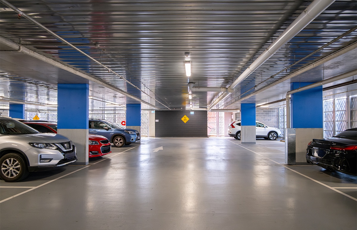 Calle de un garaje comunitario con coches ocupando algunas plazas