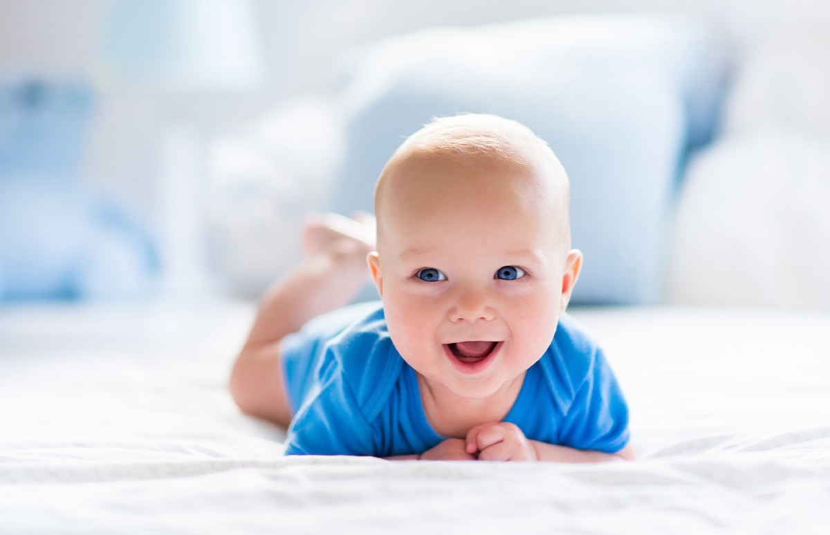 Bebé sonriente sobre una cama blanca