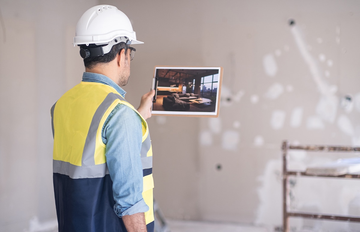 Albañil con una foto de como debe quedar la obra dentro de una habitación que esta siendo reformada