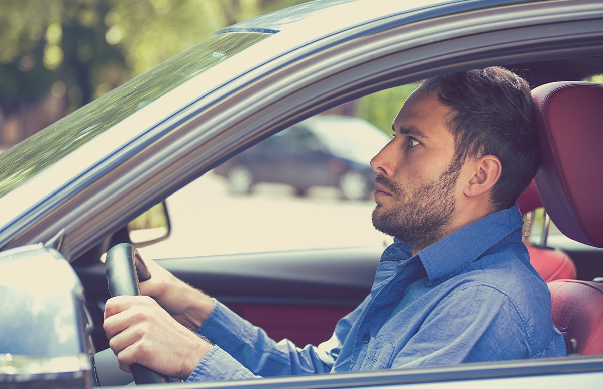 Hombre agarrado fuertemente al volante de su coche con cara de miedo