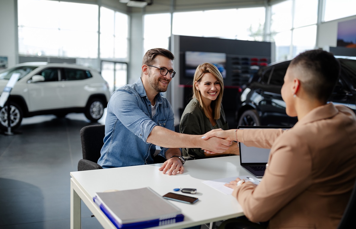 Agente dando la mano a un cliente en una venta de un coche