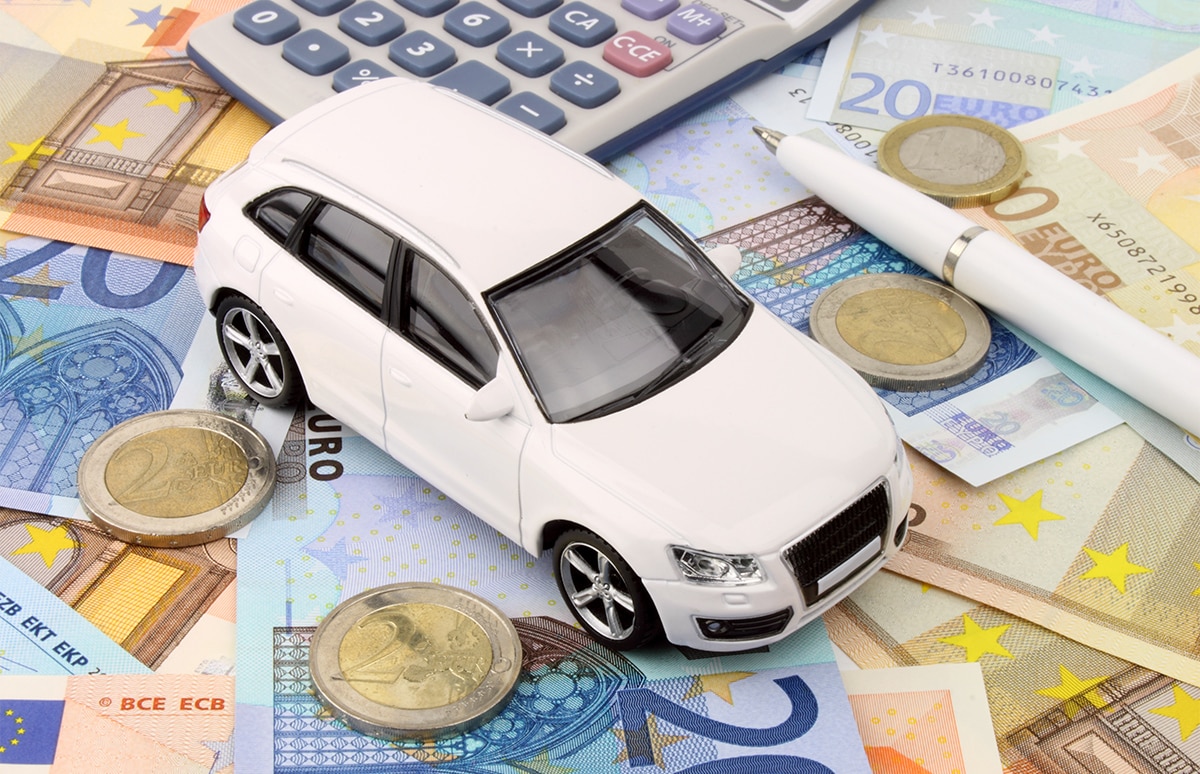 Coche en miniatura junto a calculadora y sobre dinero