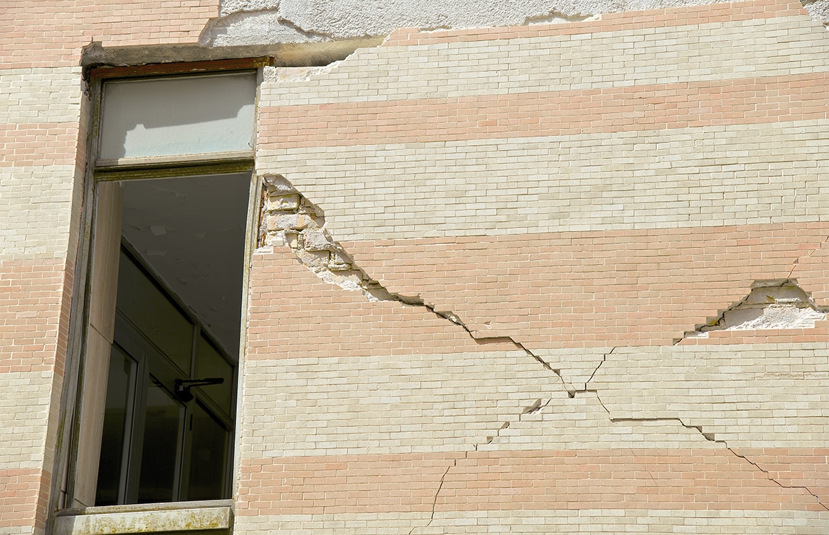 Grietas profundas y daños visibles en la fachada de un edificio junto a una ventana abierta