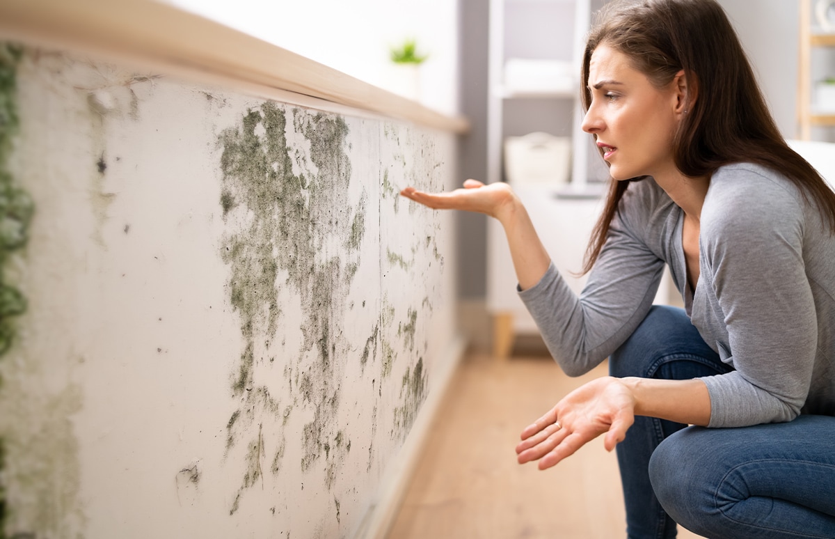 Mujer mirando una pared con humedades