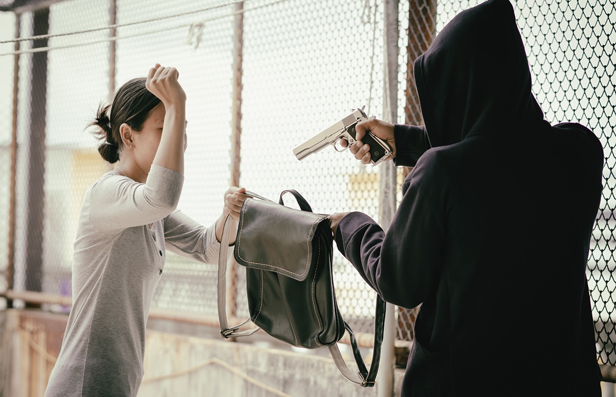 Mujer siendo atracada por un hombre a punta de pistola