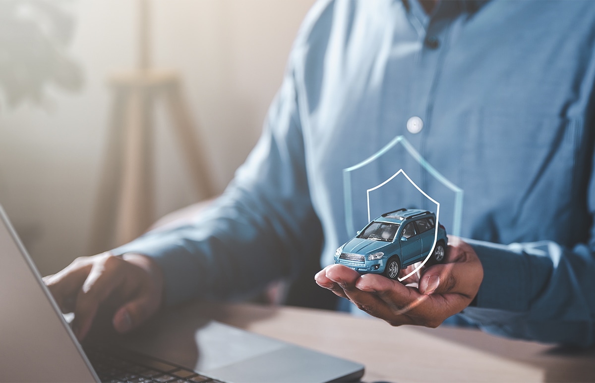 Hombre con maqueta de un coche en la mano haciendo una búsqueda en el ordenador