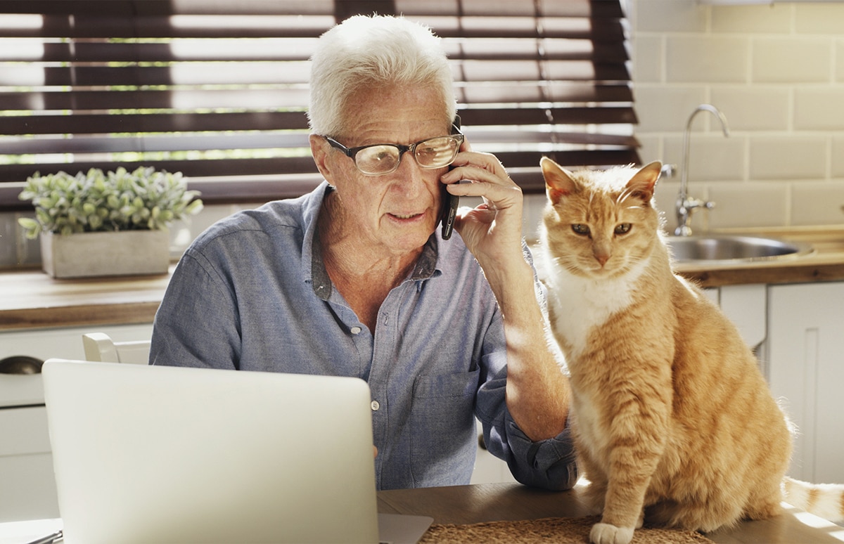 Hombre llamando por teléfono con un gato al lado