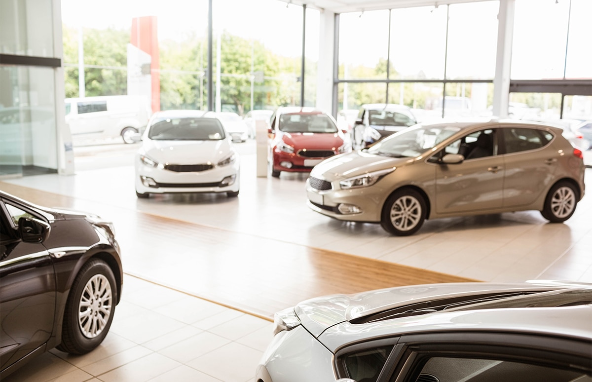 Vista interior de un concesionario de automóviles con varios vehículos expuestos, representando la compra de un coche nuevo y la importancia del periodo inicial de rodaje