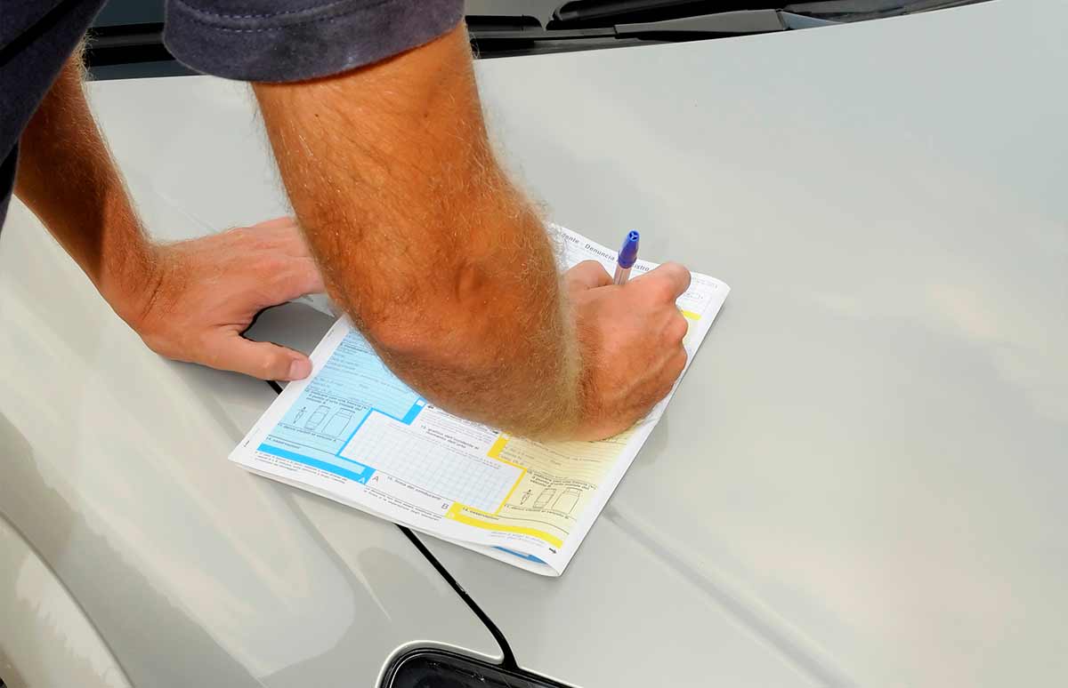 Cumplimentación de un parte de declaración de daños sobre la superficie de un vehículo para documentar un siniestro automovilístico