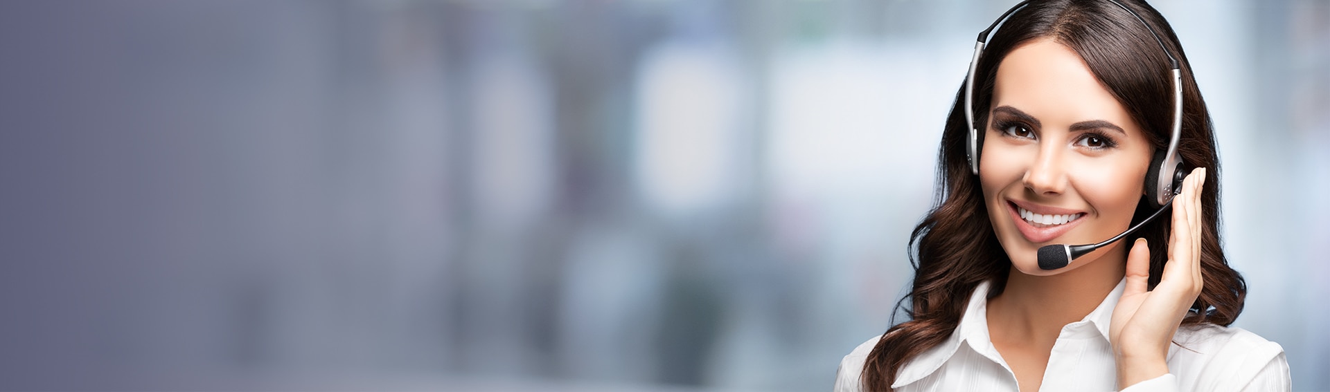 Persona con auriculares de atención al cliente sosteniendo el micrófono, sobre un fondo desenfocado de oficina