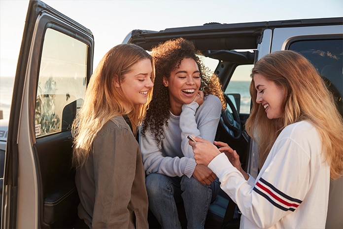 3 chicas jovenes al lado de una furgoneta sonrientes