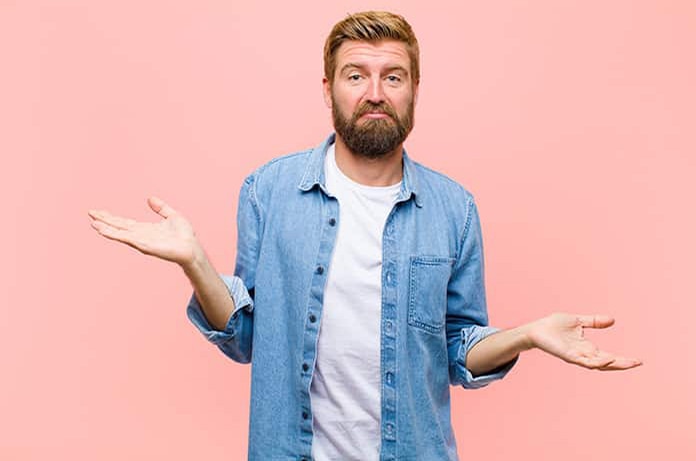 Persona con gesto de duda o desconcierto, mostrando las palmas hacia arriba sobre un fondo rosa suave