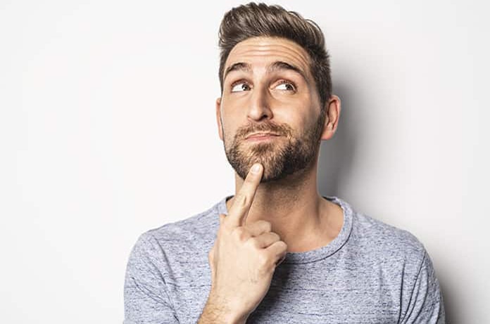 Persona tocándose el mentón en un gesto reflexivo frente a un fondo claro