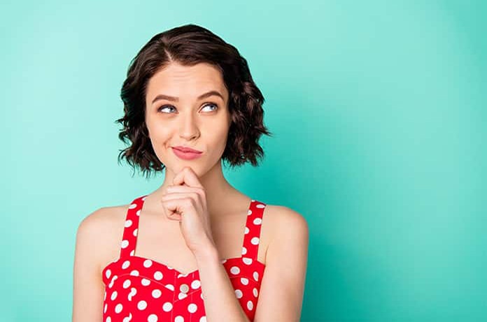 Persona con gesto pensativo, tocándose la barbilla, sobre un fondo verde turquesa