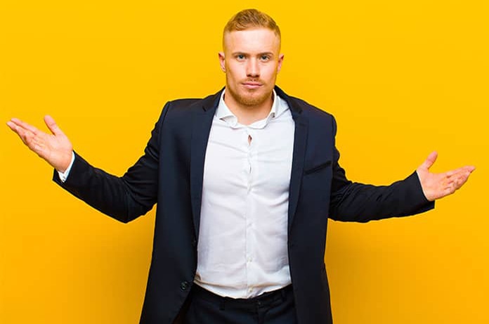 Persona con traje extendiendo los brazos en señal de comparación o duda sobre un fondo amarillo vibrante