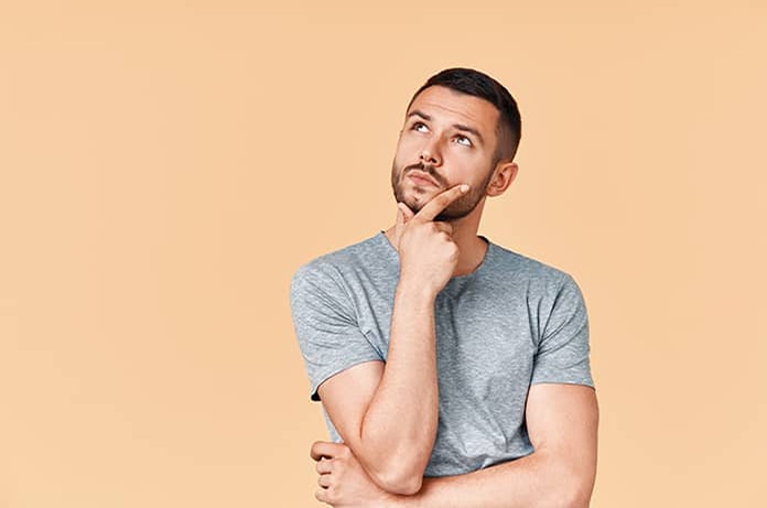 Persona con postura reflexiva, apoyando la mano en el mentón sobre un fondo color crema