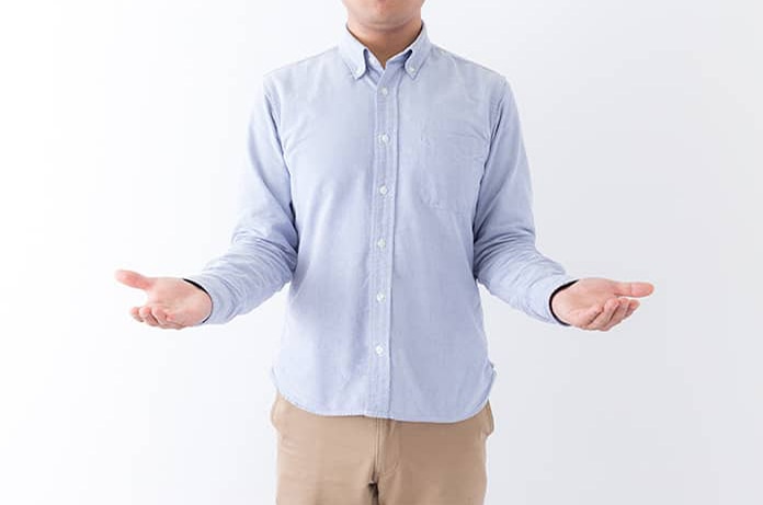 Persona con camisa clara y brazos extendidos hacia los lados, transmitiendo duda o apertura a distintas opciones sobre un fondo blanco