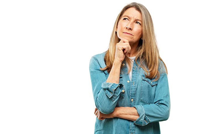 Persona con gesto de duda o reflexión, con la mano en el mentón y vestida con camisa vaquera sobre fondo blanco