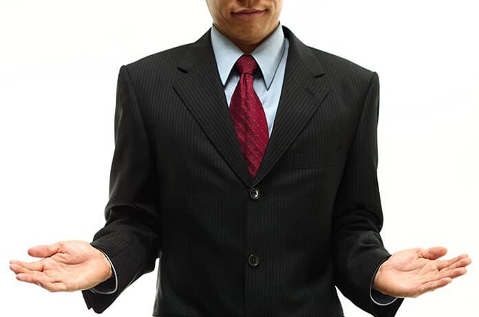 Persona con traje y corbata mostrando las palmas abiertas, transmitiendo indecisión o apertura a diferentes alternativas