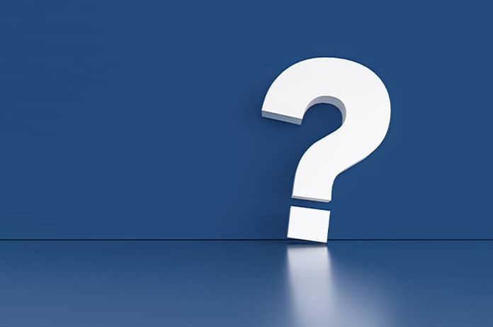 Gran signo de interrogación blanco apoyado sobre una superficie azul, simbolizando duda o pregunta