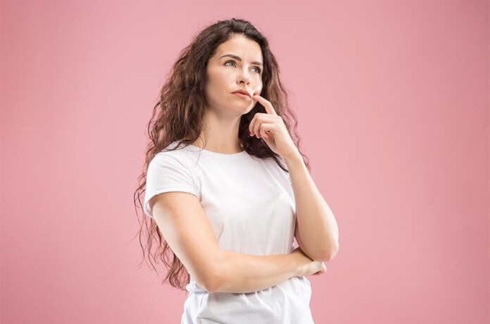 Figura con camiseta clara en postura pensativa frente a un fondo liso de color rosa