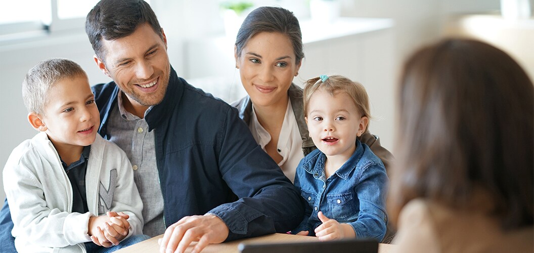 Grupo familiar sentado frente a una profesional durante una reunión en un entorno luminoso
