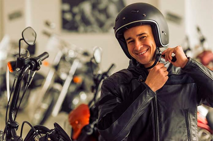 Persona ajustando el cierre del casco mientras permanece junto a una motocicleta en el interior de un establecimiento de motos