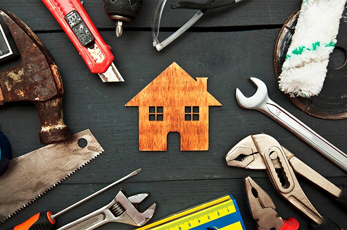 Conjunto de herramientas de bricolaje distribuidas alrededor de una figura de casa hecha de madera