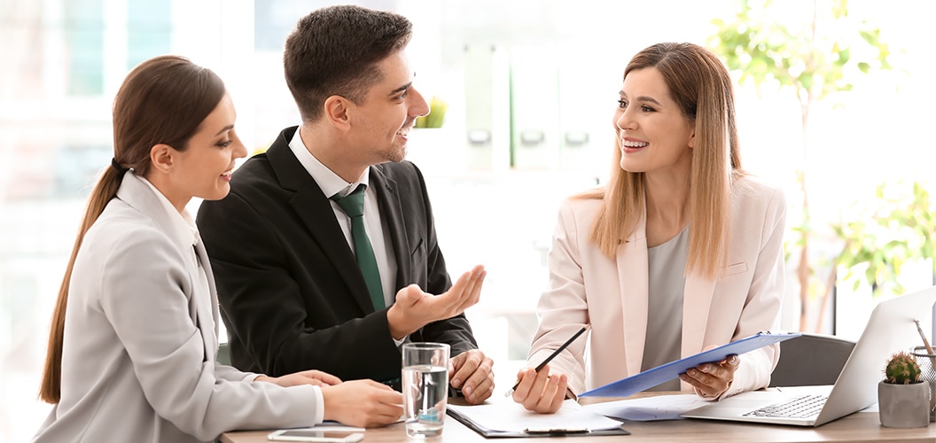 Personas reunidas en una mesa de trabajo analizando documentos y una carpeta durante una consulta profesional