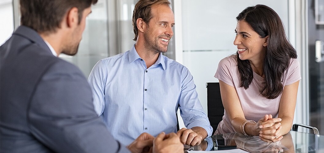 Varias personas reunidas en una mesa de oficina, conversando y revisando documentación durante una consulta presencial