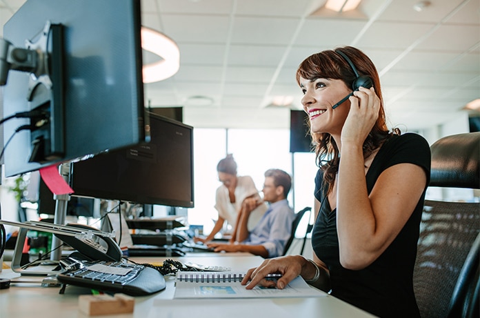 Espacio de trabajo con varias personas utilizando auriculares frente a pantallas de ordenador en una oficina amplia y bien iluminada