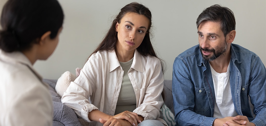 Sesión de consulta en un entorno doméstico, con varias personas sentadas en un sofá dialogando con una profesional sentada frente a ellas