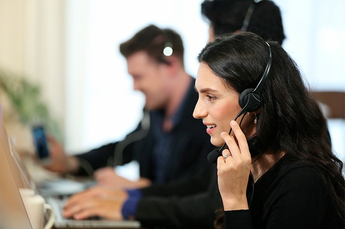 Área de trabajo compartida donde varias personas utilizan auriculares y ordenadores portátiles en una oficina moderna