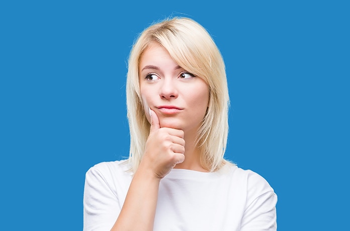 Persona en postura reflexiva con la mano apoyada bajo la barbilla sobre un fondo azul uniforme