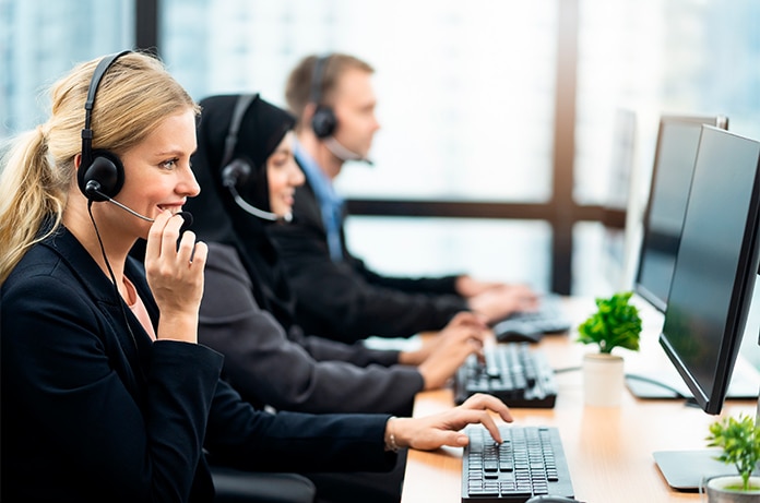 Espacio de oficina con varias personas trabajando frente a ordenadores y utilizando auriculares en un entorno profesional moderno