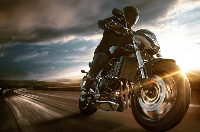 Motocicleta en movimiento sobre una carretera abierta, con efecto de velocidad y luz cálida del atardecer