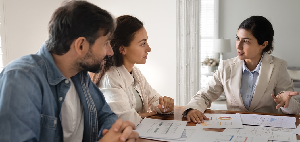 Encuentro en una oficina luminosa, con varias personas revisando gráficos y documentación durante una conversación informativa alrededor de una mesa de trabajo