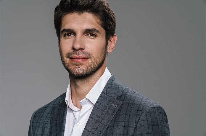Retrato de una persona vestida con chaqueta y camisa sobre un fondo neutro de estudio
