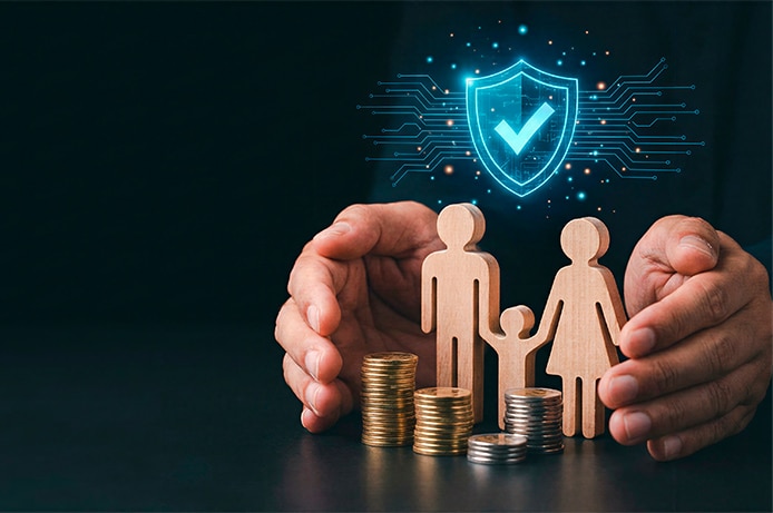 Manos rodeando figuras de madera que representan una familia junto a varias pilas de monedas, con un icono digital de escudo luminoso al fondo que simboliza protección y seguridad financiera