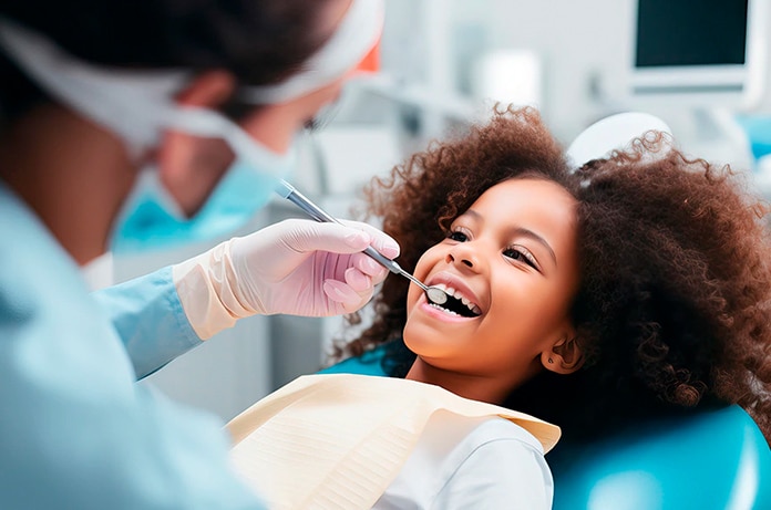 Persona reclinada en un sillón dental mientras un profesional examina la zona de la boca con instrumental clínico