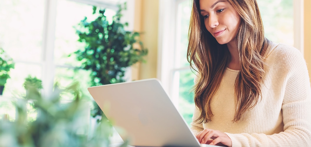 Persona utilizando un ordenador portátil en una estancia luminosa rodeada de plantas