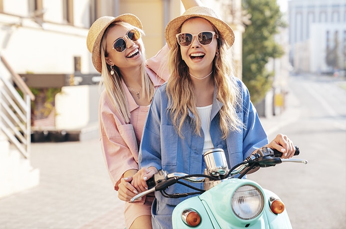 Chicas sonrientes sobre un ciclomotor color aguamarina