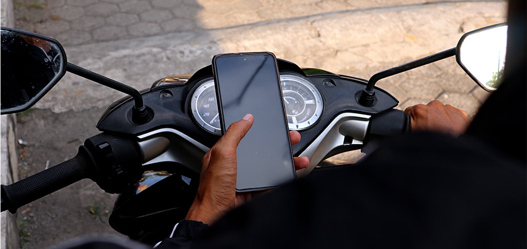 Manos sujetando un teléfono móvil frente al cuadro de mandos de una motocicleta parada