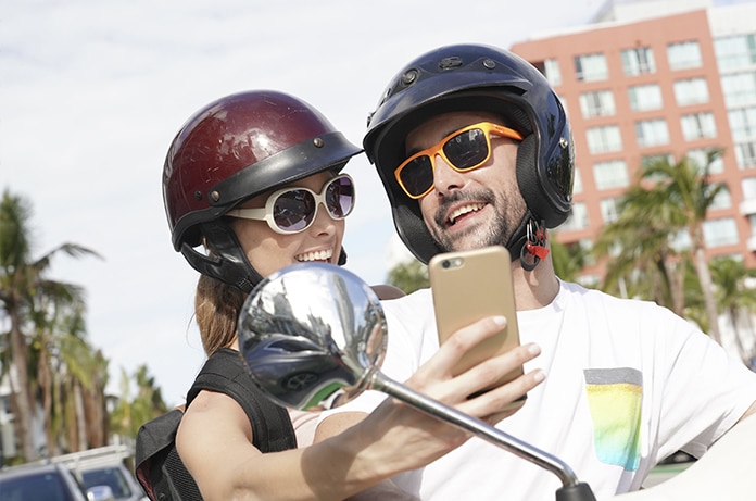 Pareja sonriente en moto eléctrica mirando el móvil