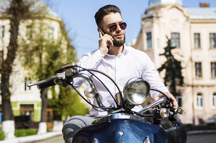 Joven sobre un scooter parado hablando por teléfono