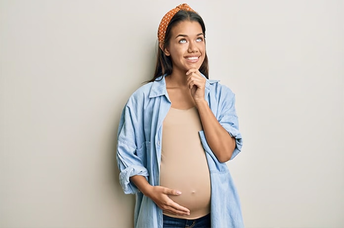 Persona sujetando el abdomen con una mano y un accesorio con la otra, en una postura asociada al embarazo