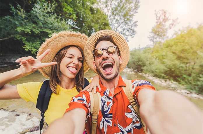 Dos personas realizando una fotografía tipo selfie en un entorno natural, ambas con sombreros de ala ancha